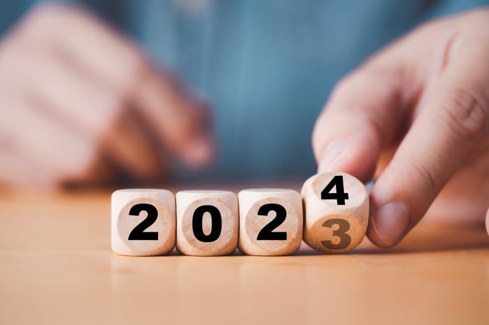 A hand turning dice to 2024.