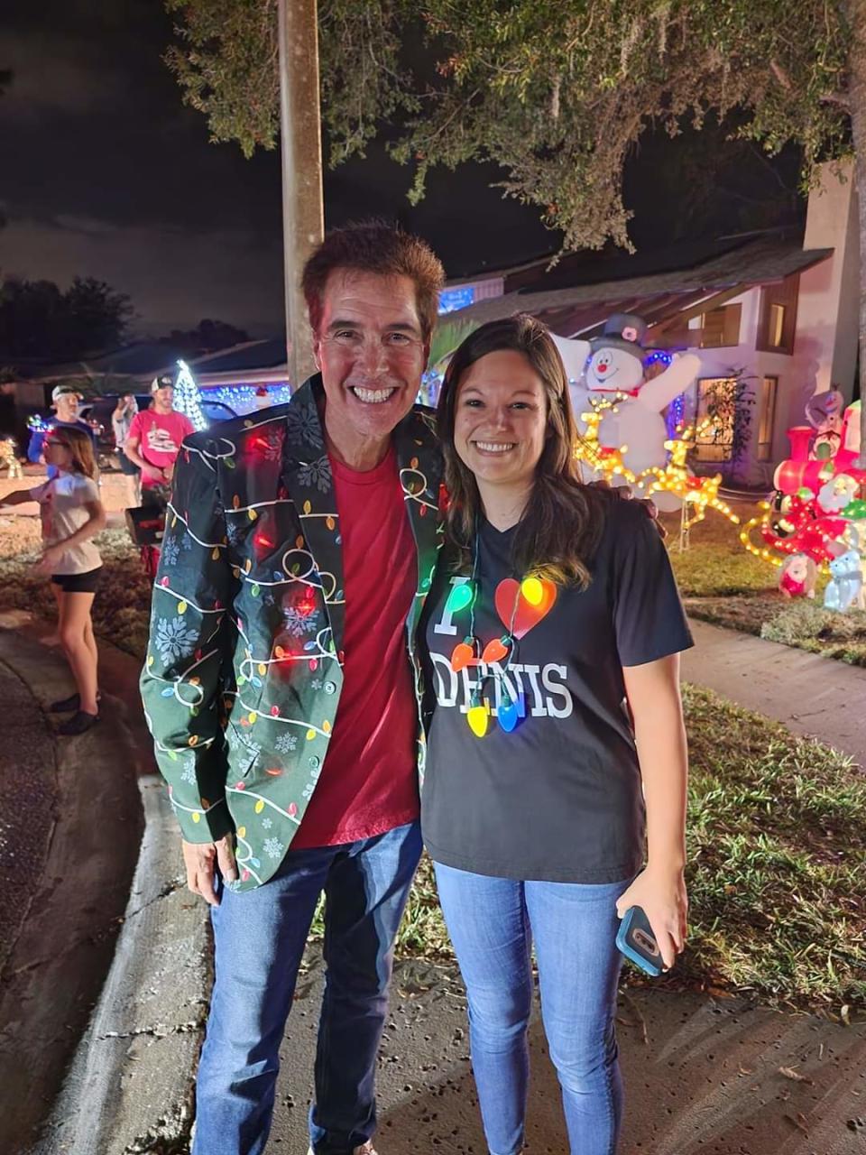 Denis Phillips, a popular TV weatherman in Florida poses for a picture with a fan during his neighborhood's holiday festivities. 