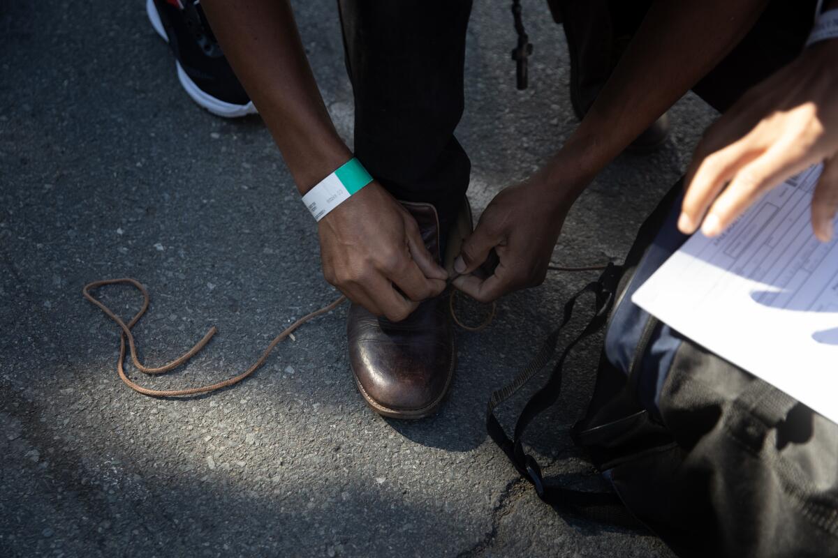 A migrant from Nicaragua laces his shoes after being dropped off at a migrant welcome center run by SBCS
