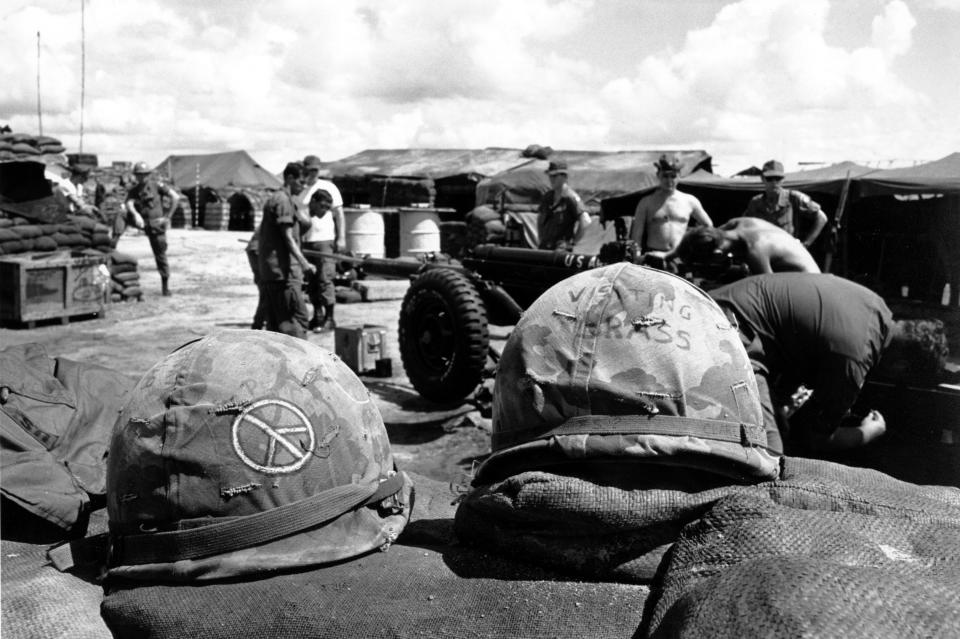 Members of the B battery, 2nd battalion, 321st Brigade, 82nd Airborn Division clean a 105mm Howlitzer in Saigon on Sept. 16, 1969. A couple of army helmets atop a sandbag wall are decorated with a peace sign, a symbol popular with this war. (AP Photo/Godfrey)