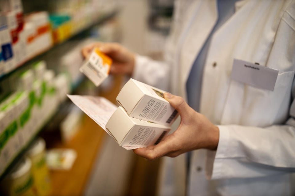 Close-up of a female pharmacist hands with prescription searching medicines in rack. Chemist looking for the medicines in storage rack.