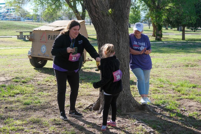 Tiffany Schuler, development director of the Epilepsy Foundation Texas, hands a young participant a trophy at the Annual Epilepsy Foundation Walk Saturday at Thompson Park in Amarillo.