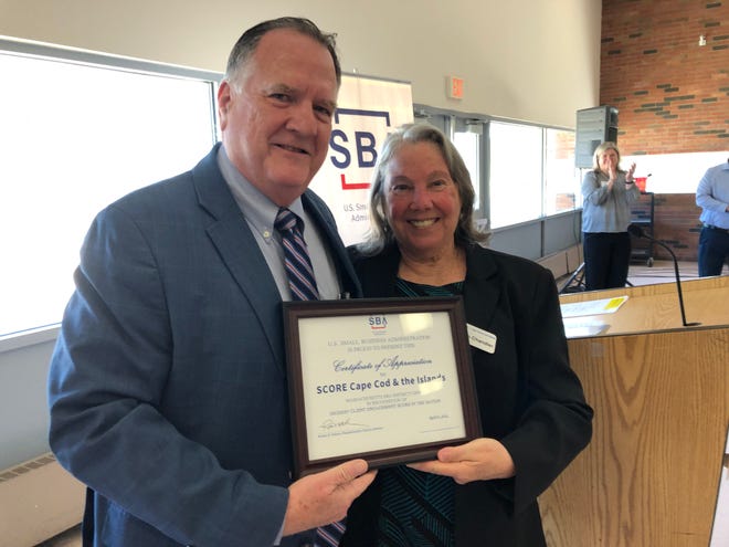 Robert Nelson, Massachusetts District Director of the Small Business Administration, gives SCORE Chairwoman Susan Chandler a certificate recognizing Cape & Islands SCORE as the number one chapter in Client Engagement in the state. Denise Coffey/Cape Cod Times
