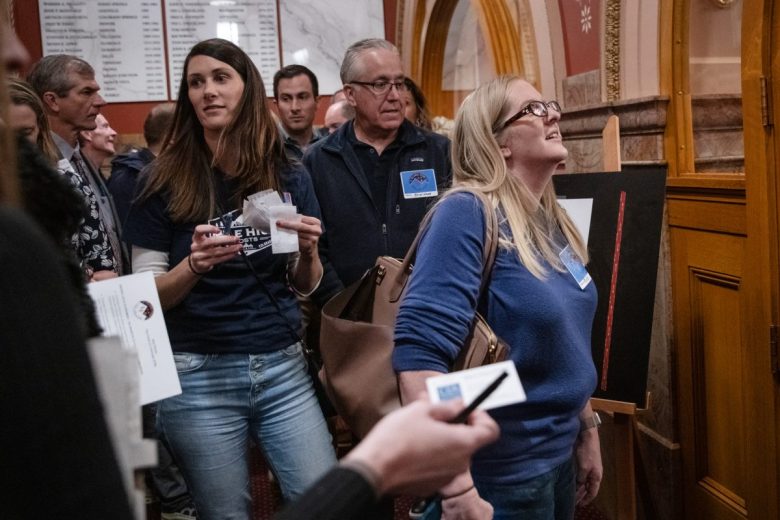 A group of people fill out name tags at the Capitol