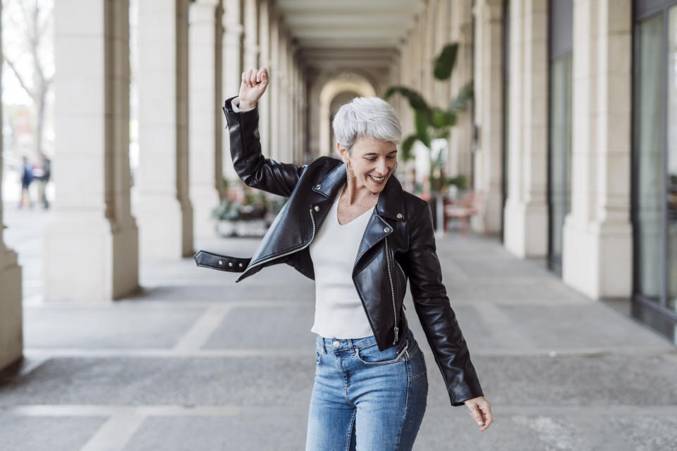 Mature woman with a positive and young attitude dancing and celebrating in the middle of the street. concept of maturity and positive personality