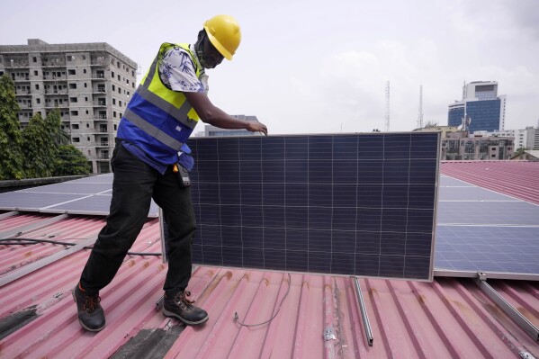 Oladapo Adekunle, an engineer with Rensource Energy, installs solar panels on a roof of a house in Lagos, Nigeria, Thursday, March 21, 2024. Funding for climate tech startups in Africa from the private sector is growing, but there's still a long way to go. (AP Photo/Sunday Alamba)