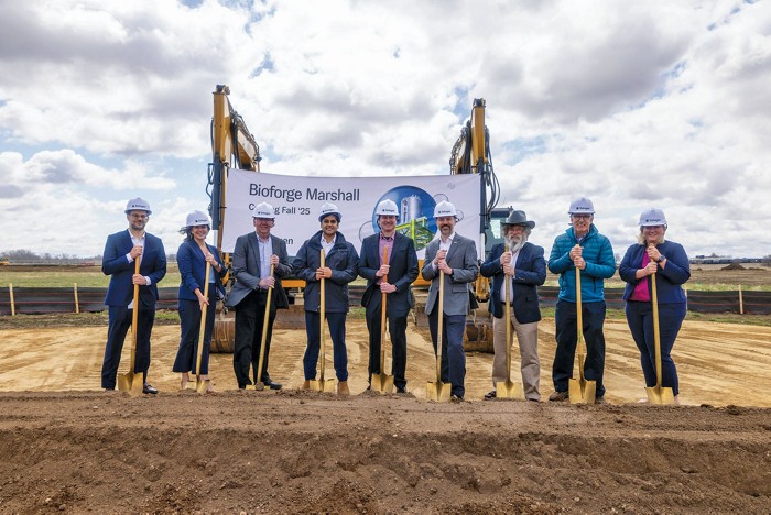 Several people stand in a line with shovels at a ground-breaking ceremony.