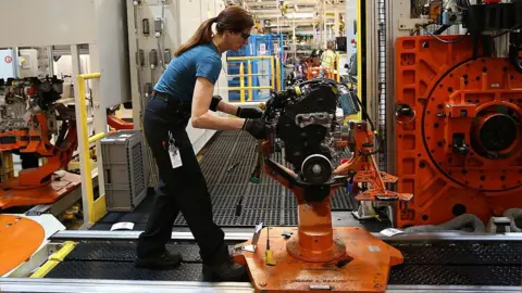 Getty Images Woman works on black and orange machine in factory
