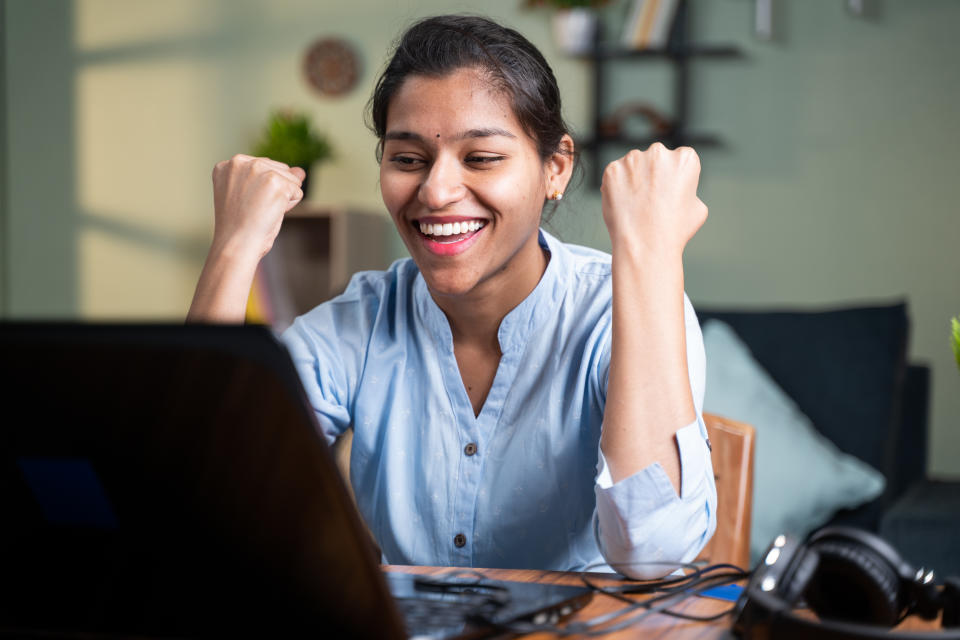 young business woman got overjoyed by good news and started celebrating while working on laptop - Concept of new Job offer or promotion, college admission and loan approvel or won the price money