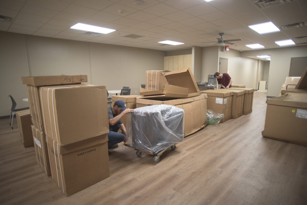 Two workers unpack boxes in a room