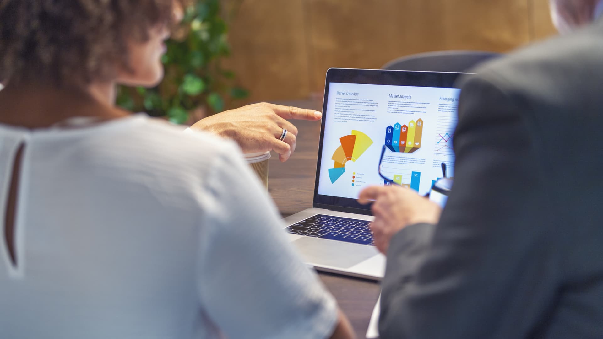 Financial advisor or business people meeting discussing financial figures. They are discussing finance charts and graphs on a laptop computer. Rear view of sitting in an office and are discussing performance