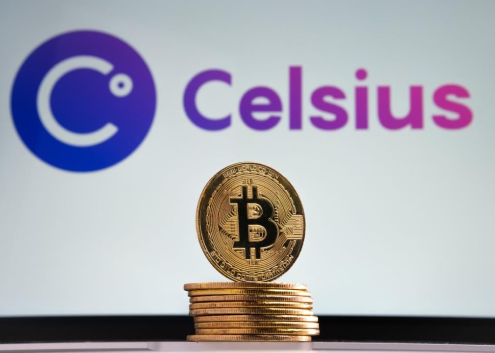A gold bitcoin standing upright on a stack of other gold coins against a background of the Celsius logo.