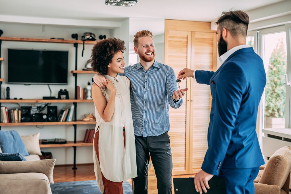 Young couple purchasing a new home, inspired by a recent survey stating that 48% of newlywed homeowners ask for down payment contributions at their weddings.
