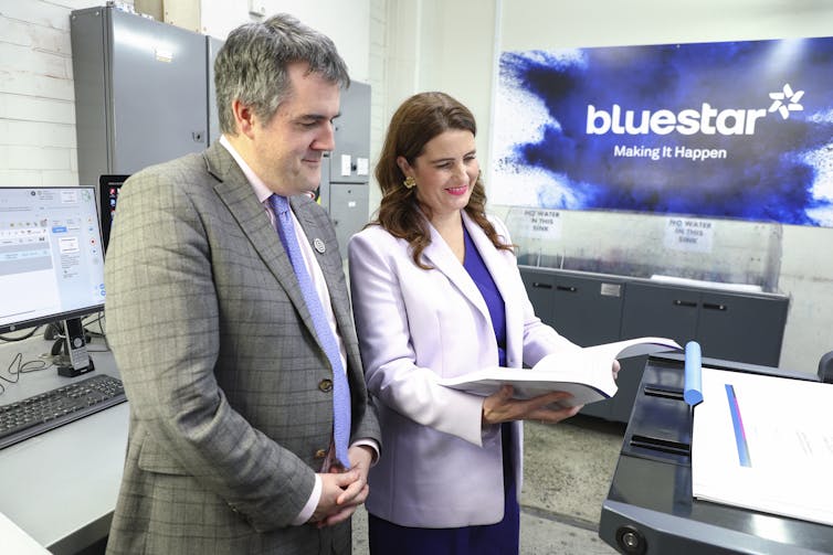 Nicola Willis and Chris Bishop look down at a copy of the New Zealand 2025 Budget.