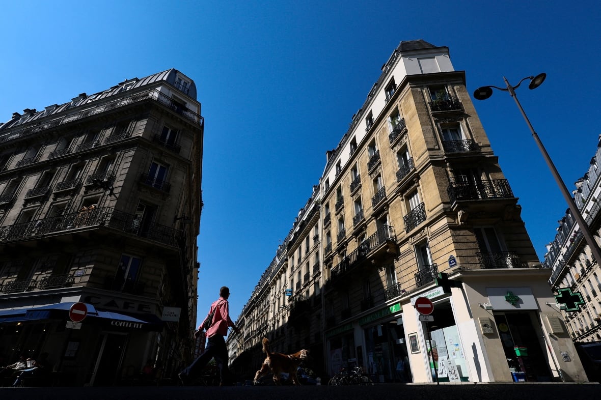 Two buildings and a narrow lane are shown from street level in a daytime photo. The buildings appear to be many decades old.