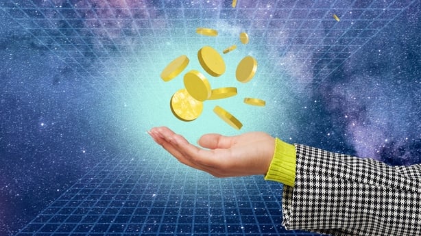 A collection of gold coins hove above a human hand in a virtual space