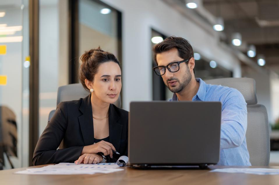 Future business planning with data-driven insights. A male project leader works with a diverse female team in a high-tech office, discussing finance, strategy, and innovation. Corporate leadership, collaboration, and digital transformation in action.