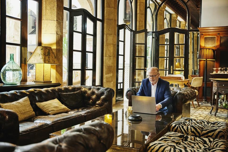 Wide shot businessman working on laptop in lounge of luxury hotel
