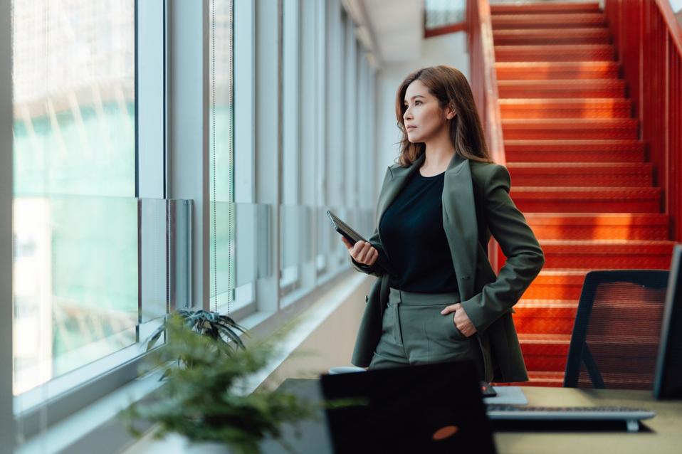 Confident young Asian businesswoman with digital tablet in office
