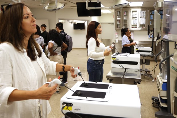 Through Chicago Cancer Health Equity Collaborative Fellows program at Northwestern University, Alexis Chappel, center, take part in a demonstration of fundamental laparoscopic surgery at a Northwestern surgical bio skills simulation lab on July 21, 2025. (Antonio Perez/Chicago Tribune)