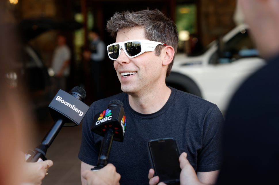 Man in white sunglasses and black t-shirt speaks to reporters outside