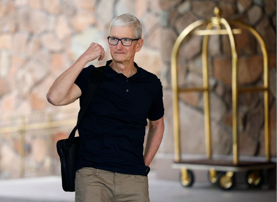 Man in black shirt and glasses walks past brick wall