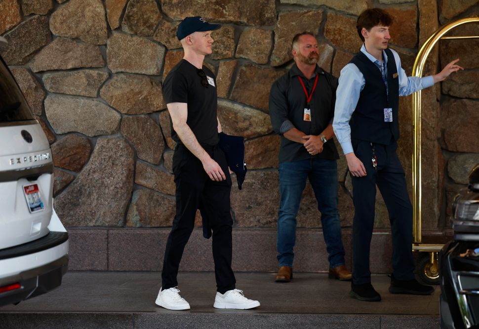Man in black shirt, pants and hat walks past stone wall