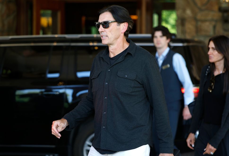Man in sunglasses and black button up walks outside 