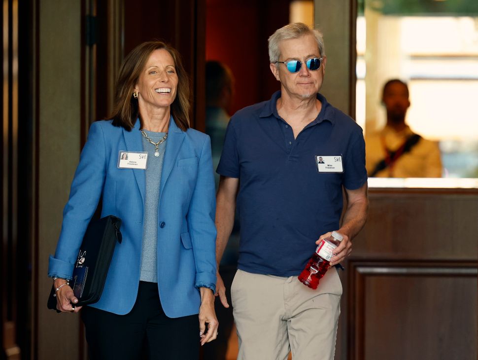 Woman in blue blazer and man in blue shirt walk outside