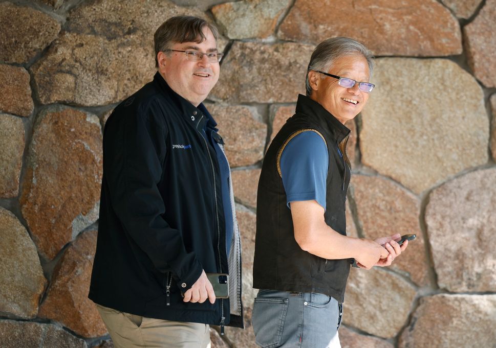 Man in black sweater and man in black vest walk outside 