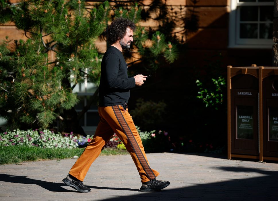 Man in black shirt and orange pants walks outside 