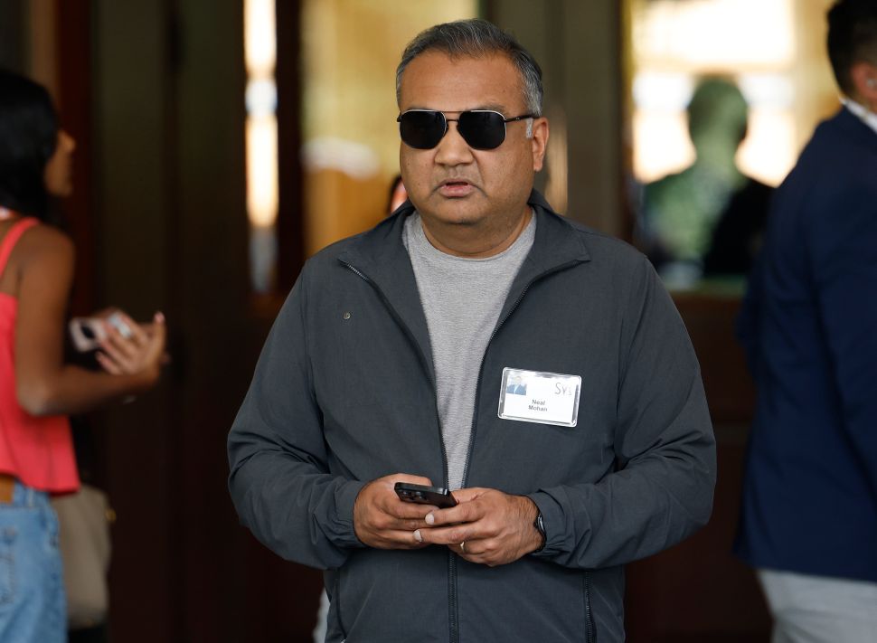 Man in grey sweater and sunglasses walks outside