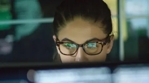 Getty Images Close up of a young woman wearing glasses looking at monitor