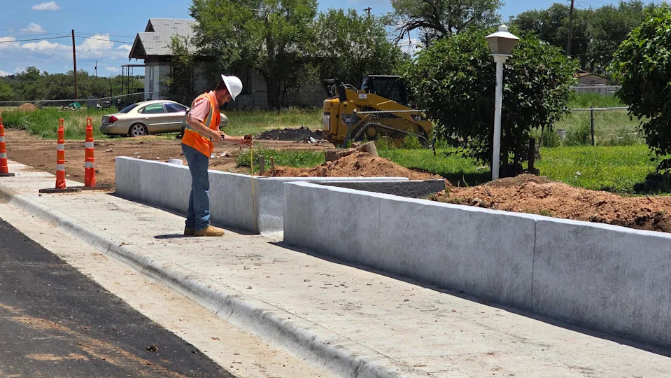 A construction worker inspects measurements along a newly built sidewalk on Northwest 18th Avenue in Amarillo’s North Heights neighborhood. The work is part of a broader effort to improve accessibility and pedestrian safety.