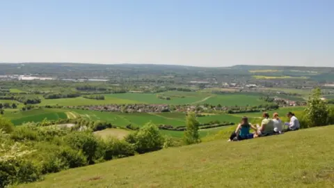 Southeastern Four people sat at the top of the hill overlooking lots of green fields