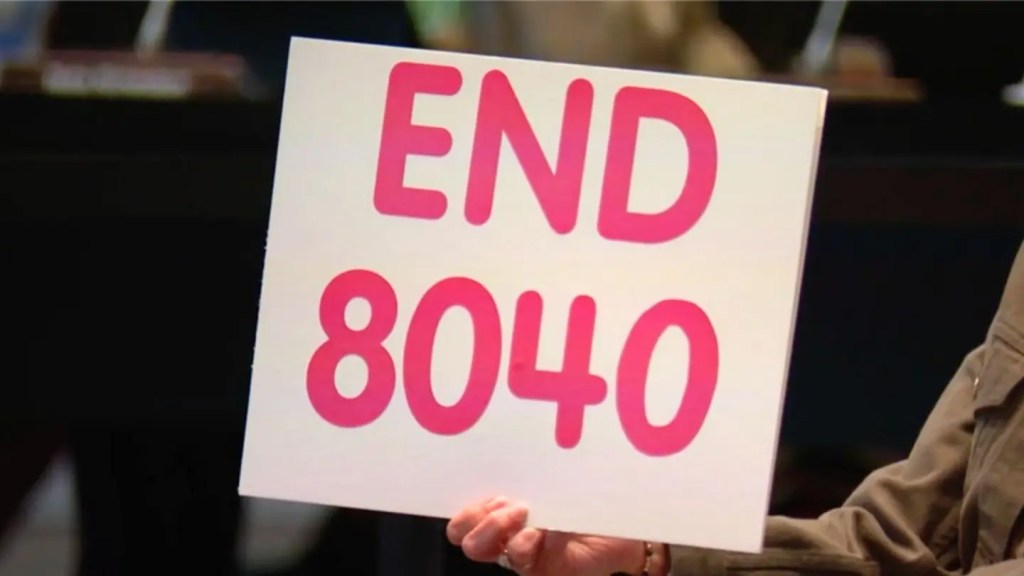 A demonstrator holding up a sign protesting Loudoun County Schools' "Policy 8040" on transgender bathroom and locker room usage.
