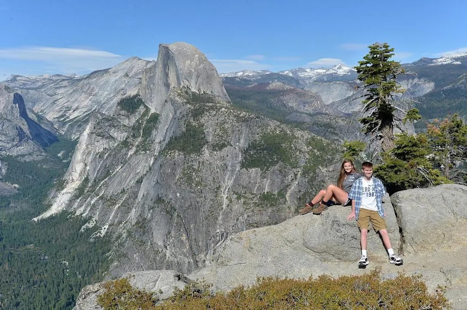 Young visitors pose for a photograph in front of Half Dome and the Yosemite Valley floor from atop Glacier Point at Yosemite National Park on Tuesday, June 14, 2016.