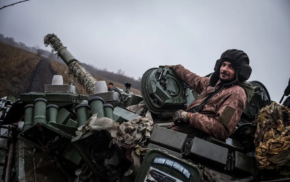 A soldier poses from the top of a tank
